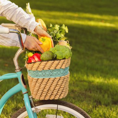 Kadın organik sebzelerle dolu sepetten taze paprika yemek istiyor.