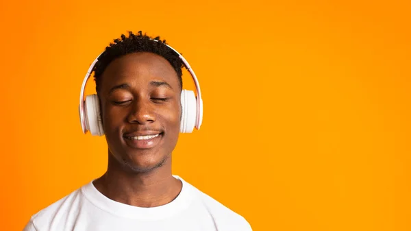 Chico africano alegre en auriculares relajante y sonriente — Foto de Stock