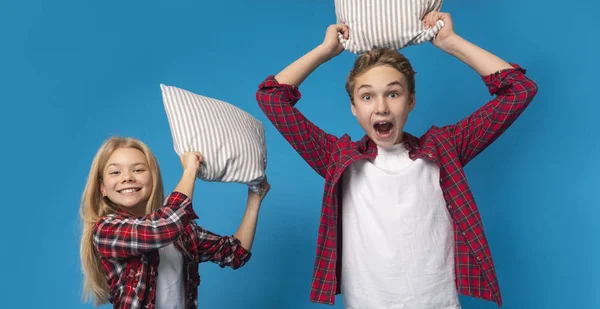 Pillow Fight. Brother And Sister Fighting With Pillows At Camera