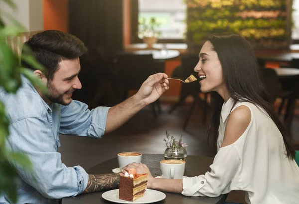 Любящий бойфренд кормит подружку дегустационным тортом в кафе — стоковое фото