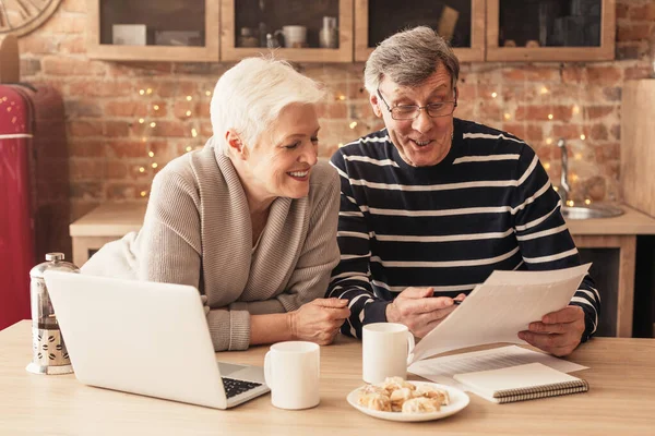 Smiling Senior Couple Reading Ziektekostenverzekering Contract In Kitchen Together — Stockfoto