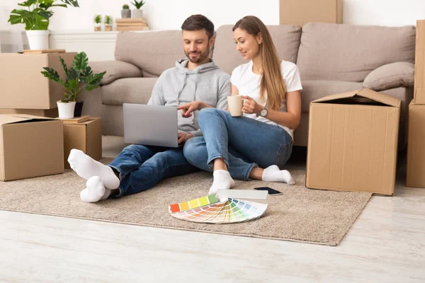 Glücklich lächelndes Paar sitzt im neuen Zuhause zwischen Kisten — Stockfoto