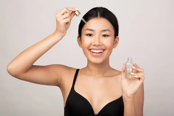 Asiatisk flicka Tillämpa kosmetisk olja på ansikte hud, Studio Skott — Stockfoto