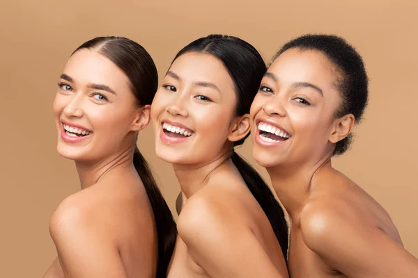 Tre diversi modelli sorridenti alla fotocamera in posa su sfondo beige — Foto Stock