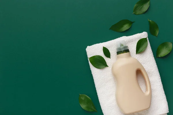 Flasche Bio-Kunststoff mit Waschmittel und sauberen Handtüchern auf grün — Stockfoto