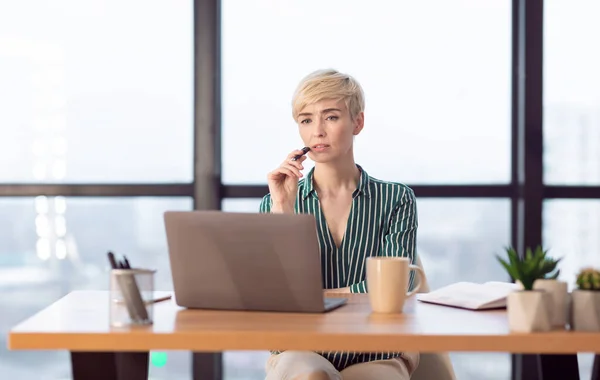Emprendedora pensando sentada en la computadora portátil trabajando en una oficina moderna — Foto de Stock