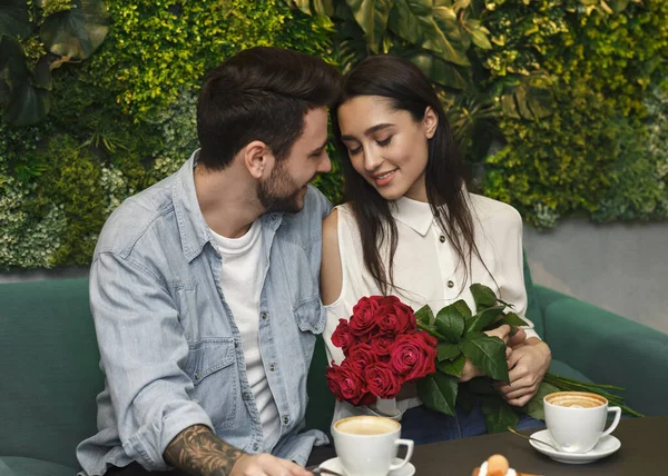 Mężczyzna dając dziewczyna róże fratulating na dzień kobiet w kawiarni — Zdjęcie stockowe