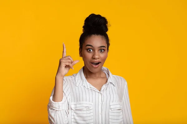 Mujer afro emocionada señalando con el dedo hacia arriba, teniendo idea o solución de problema — Foto de Stock