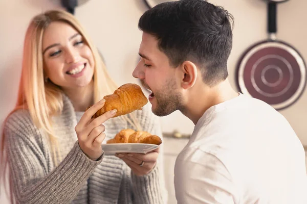 Casal jovem afetuoso compartilhando café da manhã juntos na cozinha — Fotografia de Stock