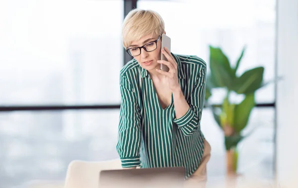 Empresaria confiada teniendo conversación telefónica en el lugar de trabajo en la oficina — Foto de Stock