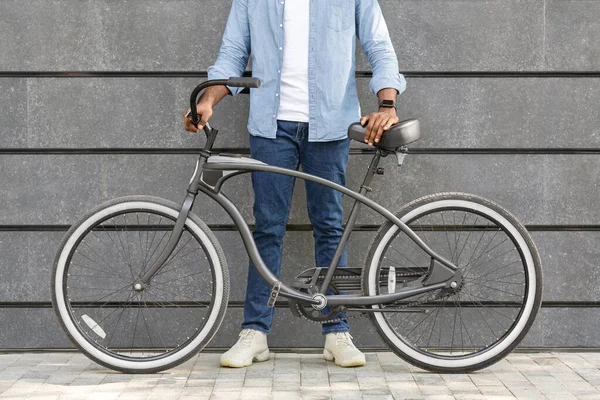 Homem irreconhecível de pé com bicicleta elegante sobre cinza parede urbana — Fotografia de Stock