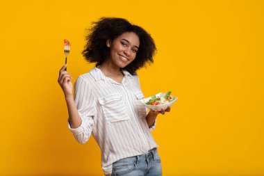 Neşeli Afro Kız Taze Sebze Yiyen, Sarı Arkaplanda Poz Veren