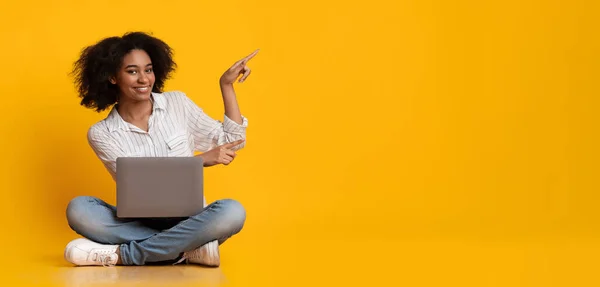 Mujer feliz con el ordenador portátil señalando el espacio de copia sobre fondo amarillo — Foto de Stock
