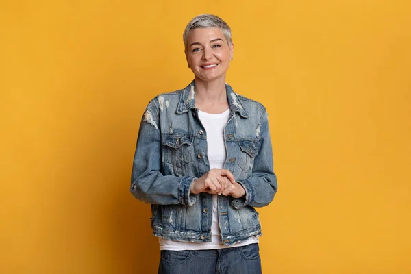 Retrato de atractiva mujer mayor en chaqueta de mezclilla sobre fondo amarillo —  Fotos de Stock