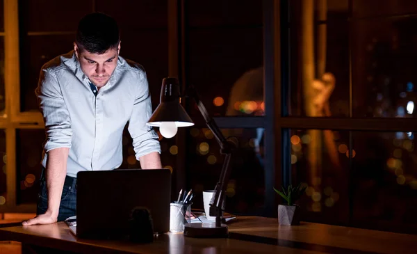 Imprenditore ragazzo in piedi lavorando sul computer portatile in ufficio di notte — Foto Stock