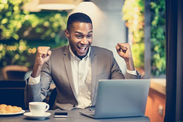 Spännande svart man firar sin seger på caféet — Stockfoto