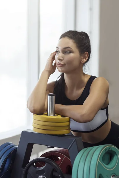 Donna atletica vicino al supporto del disco del bilanciere in palestra — Foto Stock