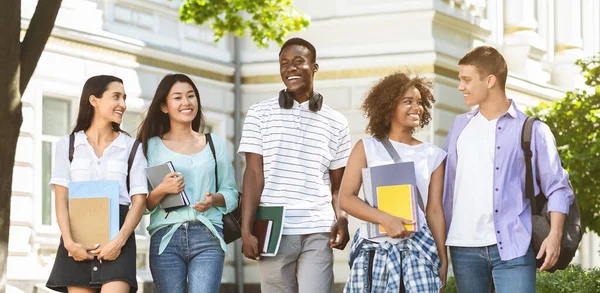 Gelukkige stagiaires wandelen buiten, samen naar de universiteit — Stockfoto