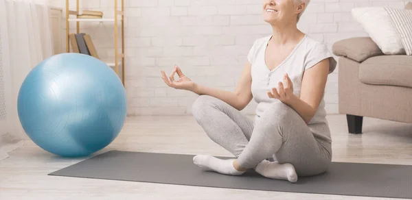Calm senior lady practicing yoga, meditating at home — Stock Photo, Image