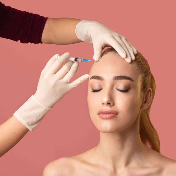 Femme obtenant l'injection de beauté dans la peau lissante de front, fond rose — Photo