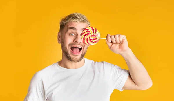 Hombre feliz cierra el ojo con piruleta arco iris — Foto de Stock