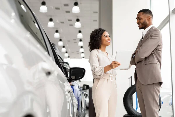 店内に立つビジネスマンに自動車を見せる自動車ディーラー女性 — ストック写真