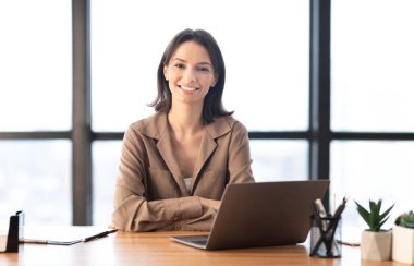 Çağdaş ofiste kameraya gülümseyen genç yönetici