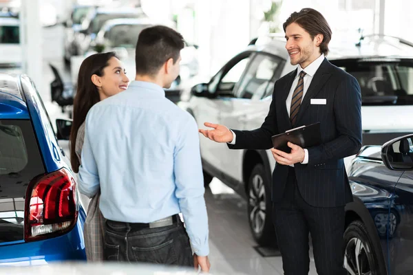 Vendedor que vende o carro aos clientes no salão de negócios — Fotografia de Stock