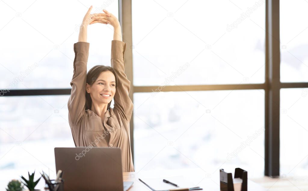 Happy american girl stretching body at modern workplace