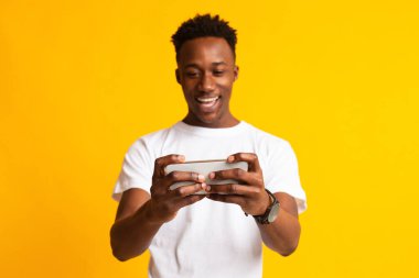 Cep telefonuyla video oyunu oynayan odaklı Afrikalı adam,