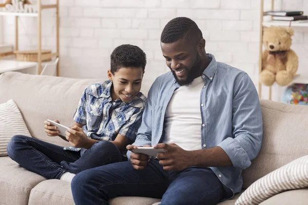Χαρούμενο μαύρο αγόρι και ο μπαμπάς του Παίζοντας βιντεοπαιχνίδια σε Smartphones — Φωτογραφία Αρχείου