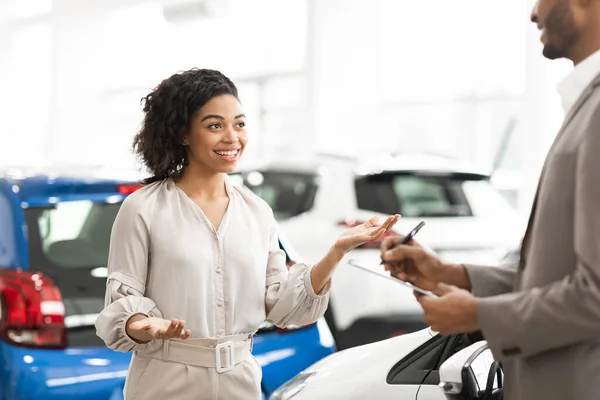 ディーラーに立つ自動車販売人と話す陽気な女性の顧客 — ストック写真
