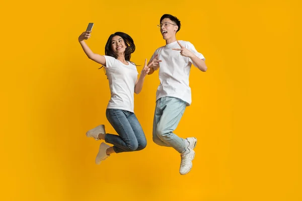 Crazy ζευγάρι ασιατική άλματα και τη λήψη selfie στο smartphone — Φωτογραφία Αρχείου