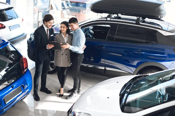 自動車ショールームでセールスマンと話しているカップル訪問車の販売代理店 — ストック写真