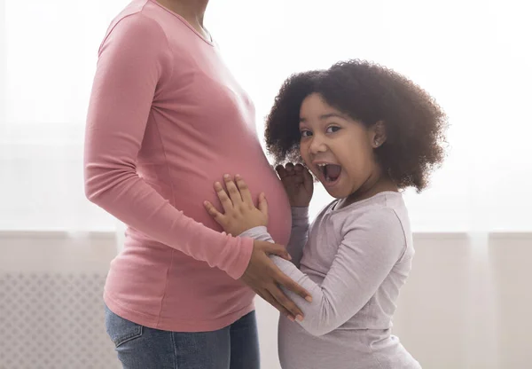 Vzrušená dívka emocionálně reagující na dítě pohyby v matkách těhotné břicho — Stock fotografie