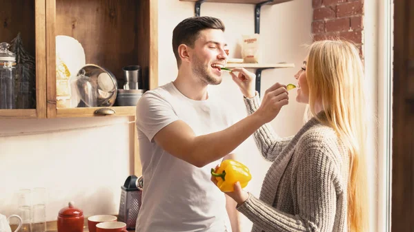 Young couple feeding each other while cooking breakfast in kitchen, copy space — Stock Photo, Image
