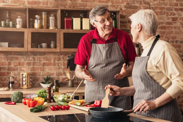 Glückliches älteres Ehepaar kocht gemeinsam gesundes Mittagessen in der heimischen Küche — Stockfoto