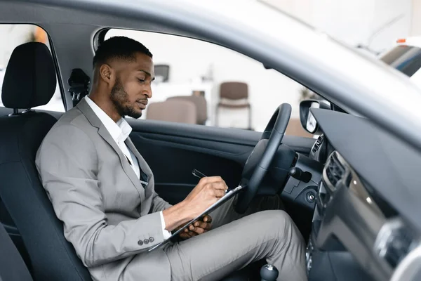 Homem tomando notas sentado em motoristas assento em Automobile Dealership — Fotografia de Stock