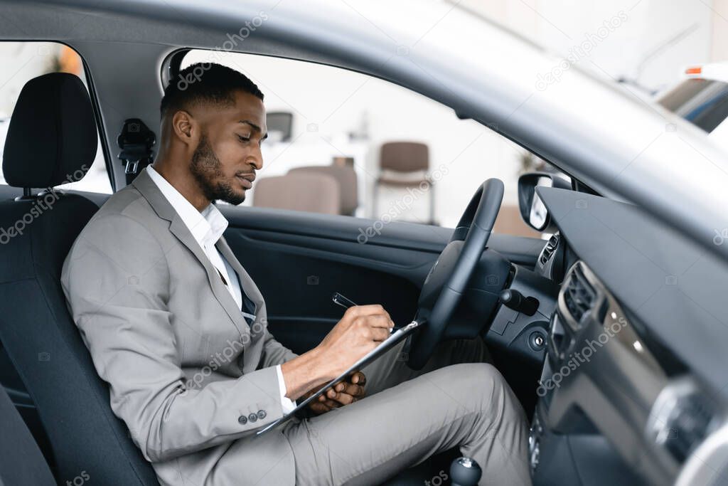 Man Taking Notes Sitting In Drivers Seat In Automobile Dealership