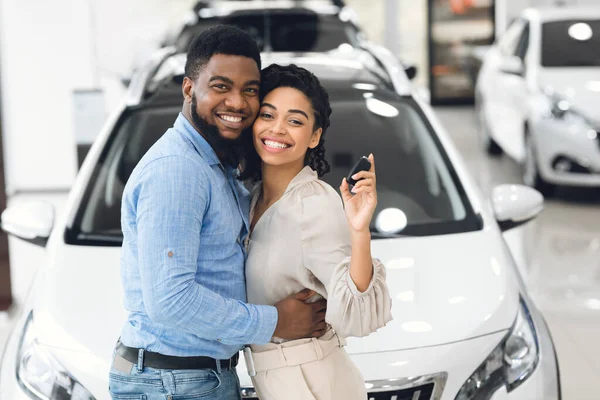 Conjoints joyeux posant étreignant et tenant la clé de voiture dans la salle d'exposition — Photo