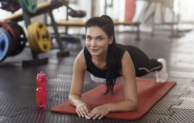Lovely young lady doing plank exercise in gym