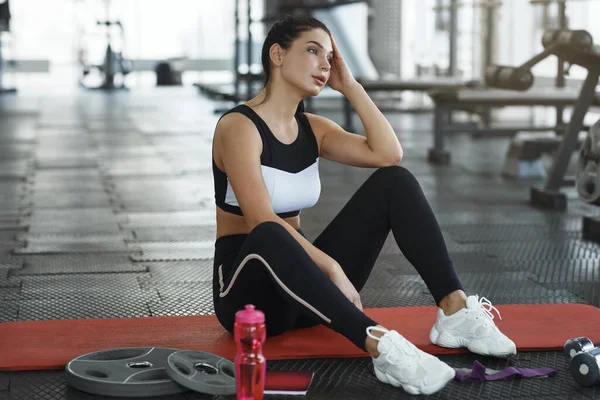 Exhausted young woman resting on yoga mat in gym — Stok fotoğraf