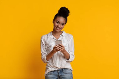 Positive Black Girl Holding Smartphone In Hands And Looking At Camera