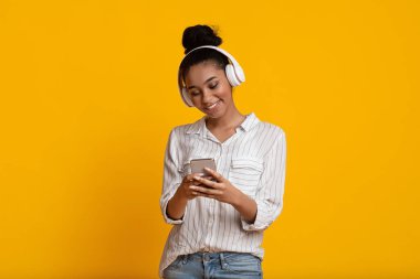 Cheerful Black Girl In Wireless Headphones Listening Music On Smartphone