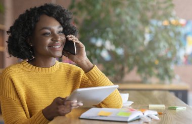 Cheerful afro businesswoman talking to client on phone
