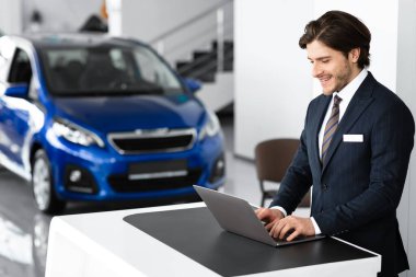 Young Car Seller Standing In Luxury Dealership Office