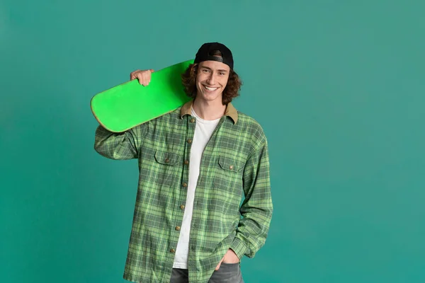 Teenage culture concept. Funky young man with skatebord on color background, space for text — Stok fotoğraf