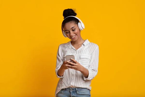 Vidám fekete lány vezeték nélküli fejhallgató Zenét hallgat okostelefonon — Stock Fotó