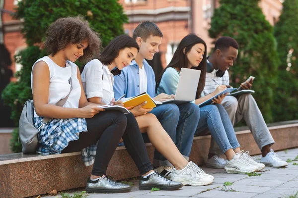 Estudiantes enfocados que se preparan para los exámenes al aire libre en el patio universitario — Foto de Stock