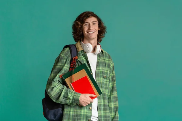 Education concept. Happy young man with backpack and notebooks on color background, blank space — Stok fotoğraf